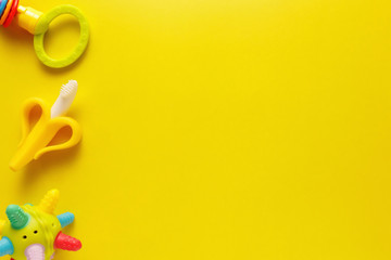 Colorful and various plastic toys for babies on a yellow background. Layout. Empty space for the text. Minimalism
