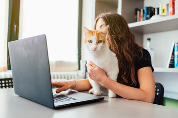 Giovane ragazza in smart woking con il gatto che le tiene compagnia 