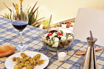 Table with foods prepare for meal of glass of red wine salad bowl and olive,green chili, anchovies skewers Spanish traditional food. photo  