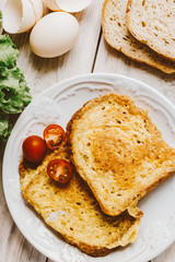 French toast, fried in eggs, lies in a plate on a light wooden rustic table. tinted beige