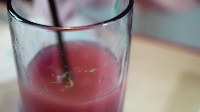 Glass with red water and paint brush in it. It's cleaned and washed by artist.