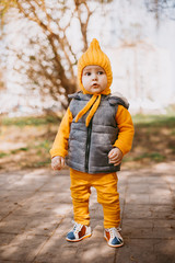 Fototapeta premium Stylish little one-year-old boy in a yellow hat, yellow pants and a gray jelly