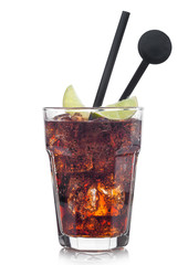 Cuba Libre Cocktail in glass with ice cubes and slice of lime with black straw and stirrer on white.