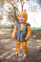 Fototapeta premium Stylish little one-year-old boy in a yellow hat, yellow pants and a gray jelly