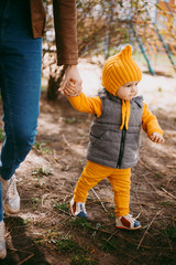 Stylish little one-year-old boy in a yellow hat, yellow pants and a gray jelly