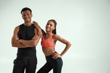 Sporty and healthy. Young african fitness couple in sportswear looking at camera and smiling while standing against grey background