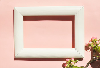 White wooden frame on a pink background with flowers. The concept of a beauty blogger, a place for text.