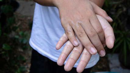 A boy in a white shirt is cleaning both hands with alcohol gel. To prevent the spread of the covid-19 virus..