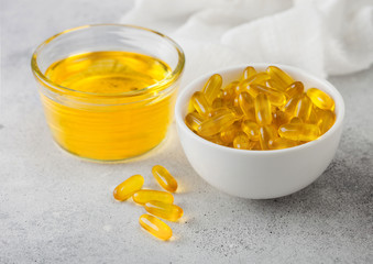Bowl of raw natural organic linseed flaxseed oil and omega 3 capsules on light table background.