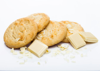 White chocolate biscuit cookies with chocolate blocks and curls on white background.