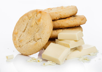 White chocolate biscuit cookies with chocolate blocks and curls on white background.