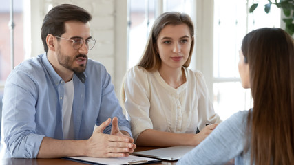 Diverse young recruiters speak with female job candidate at interview in modern office, concentrated employers discuss ideas with woman work applicant at recruitment talk, employment concept