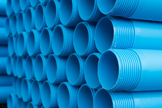 Blue plastic pipes laid on special metal shelving. Production and marketing of plastic pipes