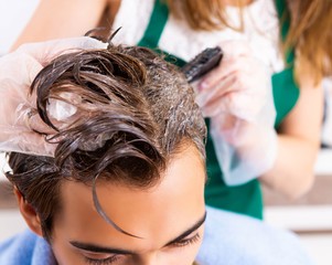 Woman hairdresser applying dye to man hair