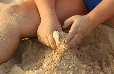 A boy plays in the sand on the beach near the sea.