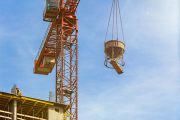 Naklejka premium One high-rise crane against a house and sky during the construction phase. Industry concept for low-income young families. Mortgage, business, real estate loan. Sunny day.