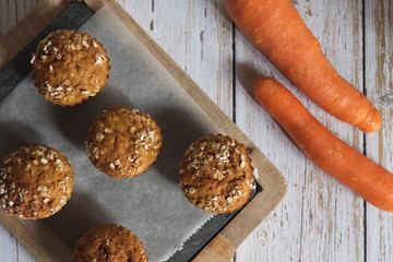 Fresh homemade delicious carrot muffins decorated with oat flakes and brown sugar on rustic table