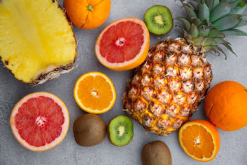 Ripe pineapple and other tropical fruit - orange, kiwi, grapefruit on grey background
