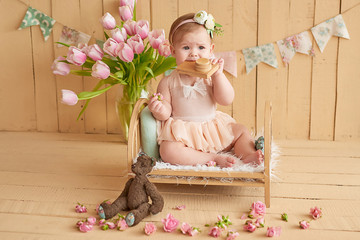 Fototapeta premium Sweet funny baby in hat with flowers. Easter greeting card, copyspace for your text. Poster for Easter holiday. Congratulations on Mother's Day. Cute baby girl with flowers. Children's Day.