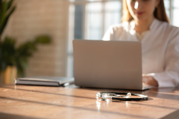 Female nurse sit at wooden desk in private clinic working on laptop consulting client online, woman...