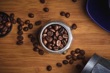 Coffee beans in a geyser coffee maker and on a wooden table. Top view.