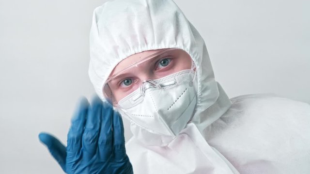 Medical worker. COVID-19 diagnostics. Female doctor in white protective coverall face mask inviting patient.