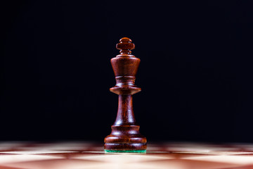 black chess king on a chessboard on a black background