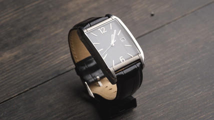 Black watch on wooden surface. - obrazy, fototapety, plakaty