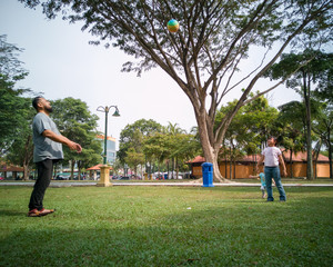 Fototapeta premium Family of three playing ball in the Malaysia park.