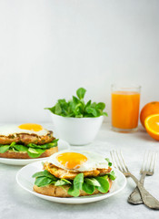 European breakfast Sandwich with fried egg, chicken, herbs and orange juice. A sandwich. Breakfast on a light table, side view.