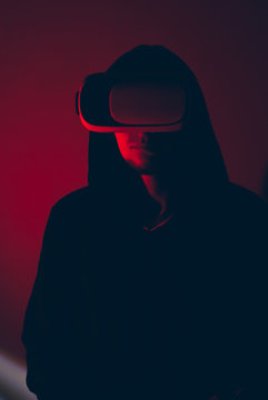 A hacker in the VR glasses in red light, the gamer in the virtual space,