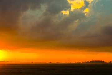Sunset on the field. Beautiful sunset landscape with large field and a forest on background