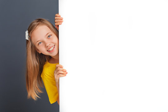 Smiling little girl looking behind a white board