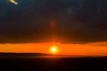 Sunset on the field. Beautiful sunset landscape with large field and a forest on background