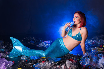 Fantasy stupid mermaid in deep ocean. Plastic trash and bottles pollution in ocean. Ecocatastrophe,...