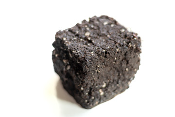 A separate object in the form of a cube from the soil on a light background in soft focus