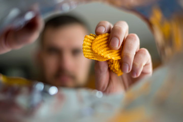 A bearded man takes chips from the package, photo from the package.