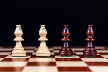 four chess bishops on a chessboard on a black background