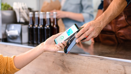 Young Woman is Using Contactless NFC Payment App Installed on Her Smartphone to Pay for Gourme Street Food. Eco Friendly Gluten Free Food Court Selling Modern Fusion Cuisine