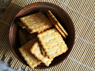 A lot of square cookies with sesame seeds in a brown plate, top view