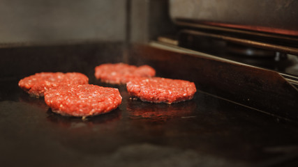 Tasty Close Up Shot of a Meat Patty Being Prepared on a Griller. Fresh Ground Beef is Grilled on a Hot Gas or Electric Grill. Cook is Seasoning a Patty for Burger from Fresh Minced Meat with Salt.