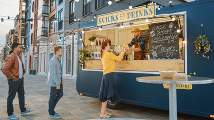 Food Truck Employee Hands Out a Freshly Made Gourmet Burgers to a Happy Young Men and Women in...