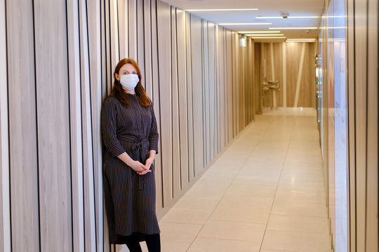 Red-haired Woman In The Hospital Lobby With A Medical Mask On Her Face