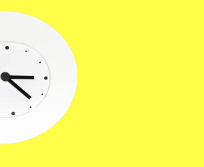 white wall clock on yellow background with copy space