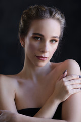 Portrait of a beautiful girl in the studio on a black background close-up. The girl has her...