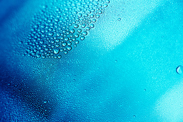 Drops of water on a transparent surface. A collection of drops in one place. The background is made of small droplets of water in blue and cyan colours. Wallpaper on the desktop.