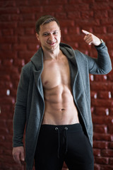 fashion boy with naked torso on the reed wall