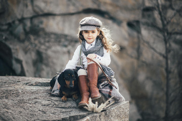 girl sitting on the edge of a stone in a bedspread with a dog