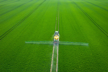 Green Fields. Aerial view of the tractor spraying the chemicals on the large green field....