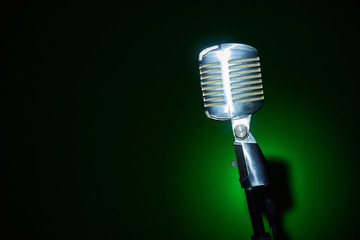 Studio retro condenser microphone on green spot light background